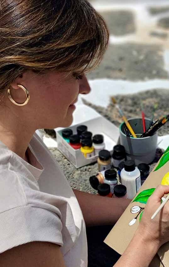 Detalle de Angie Vasquez pintando un bolso